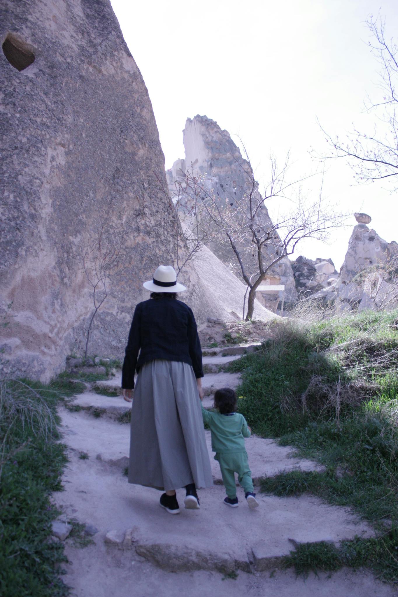 A woman and child walking on a rocky pathway in Cappadocia, Türkiye, highlighting its unique landscape.